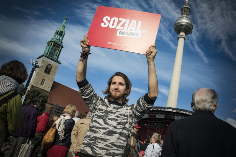 Jemand hält ein Plakat mit der Aufschrift "Sozial" nach oben